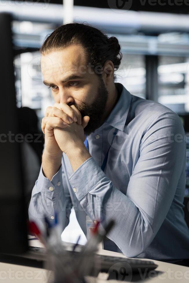 Technician in server room worried after reading diagnostic report showing critical hardware malfunction on PC. Engineer perturbed by error notifications risking network stability and system uptime photo