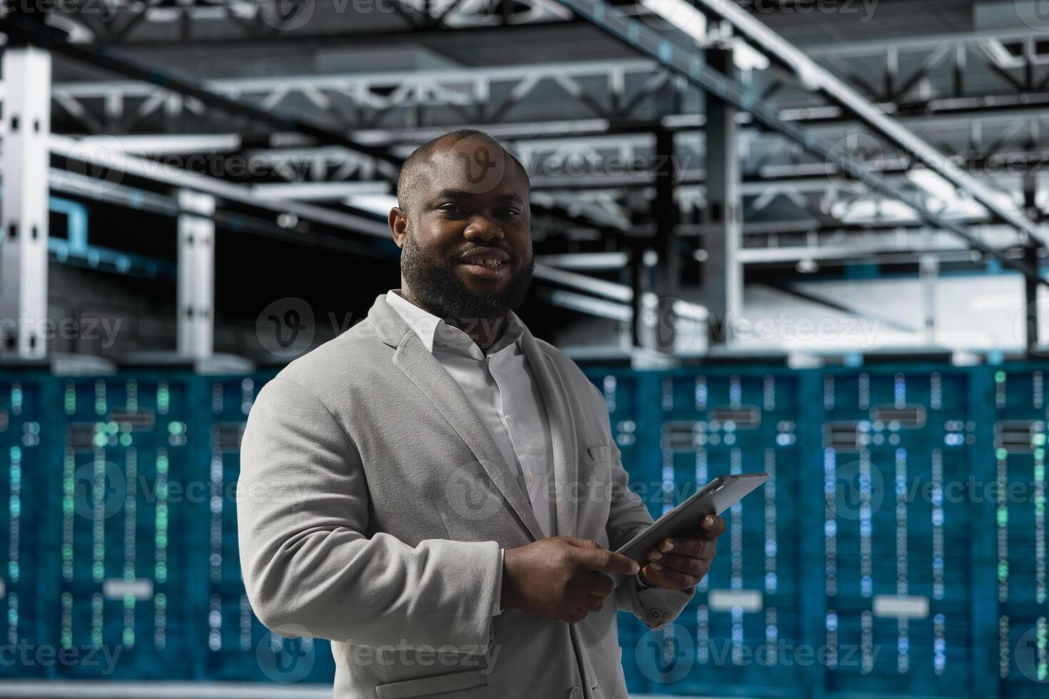 Portrait of cheerful technician in server hub checking recovery plan on tablet, monitoring energy consumption. Jolly data center staff member uses device, making sure sensors are functioning optimally photo