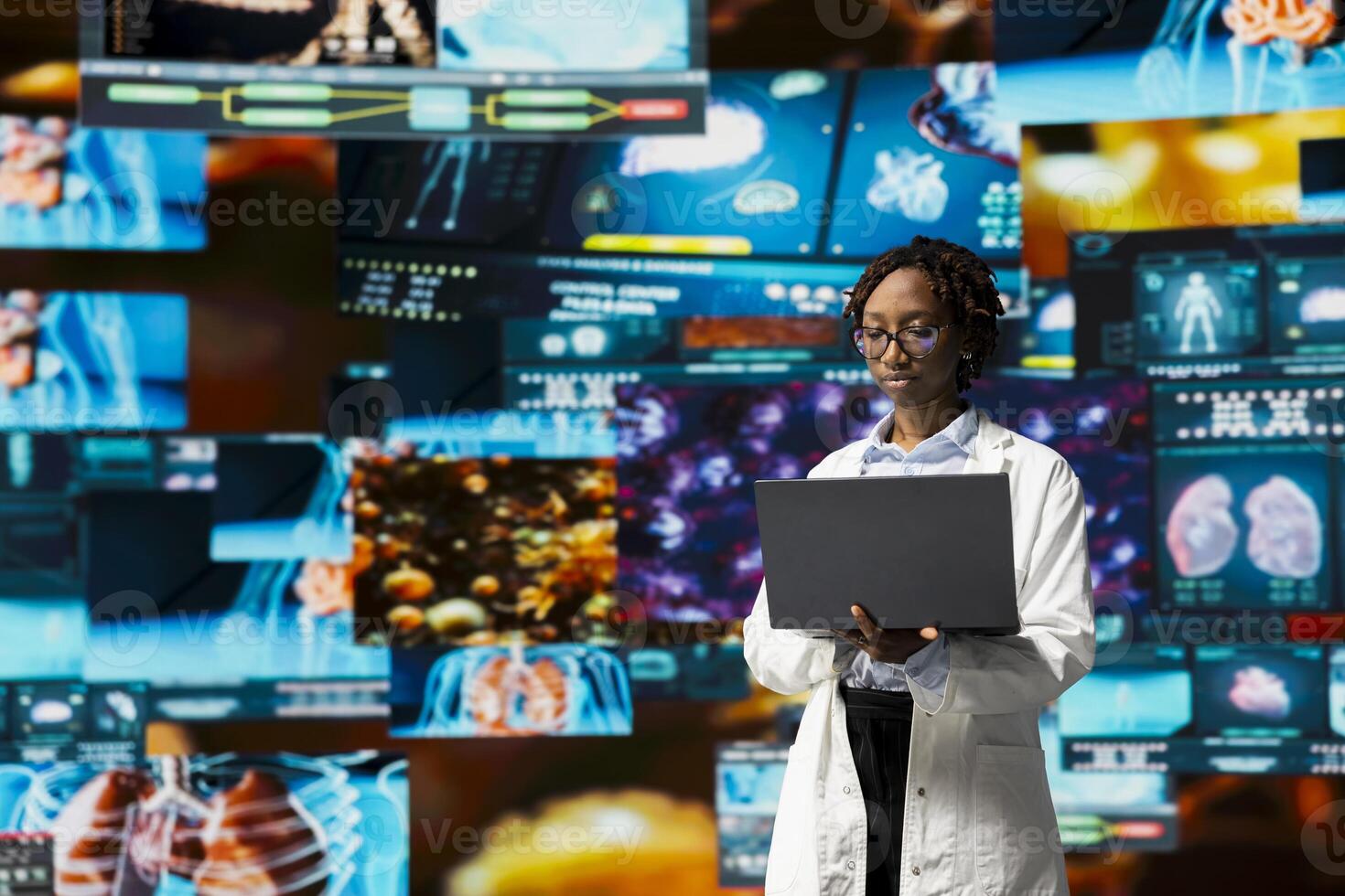 Doctor in lab coat monitoring medical research data and 3D anatomy models dashboards with laptop software. Clinician using notebook to project visual medical reports on multimedia wall photo