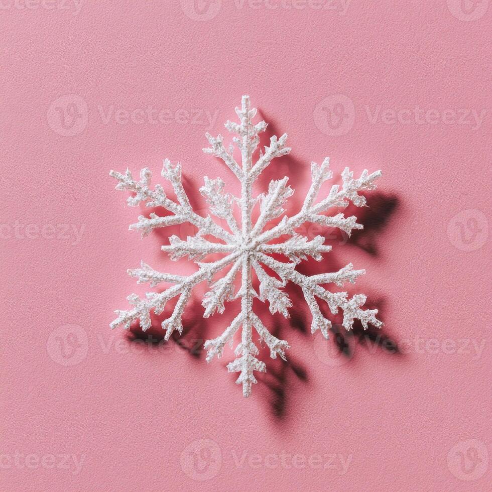 A close-up of a white, sparkly, artificial snowflake casting a shadow on a light pink background photo