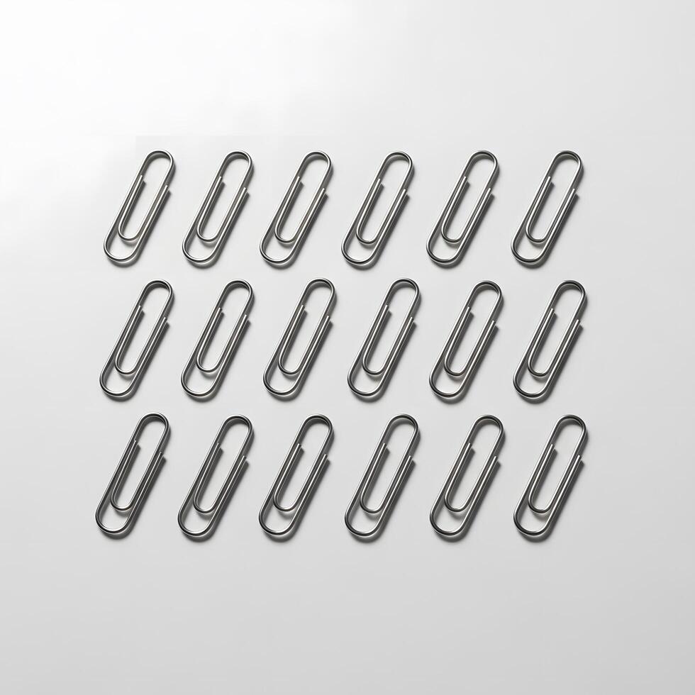 A minimalist flat lay of multiple metal paper clips neatly arranged in an orderly grid pattern on a clean white background for office concepts photo