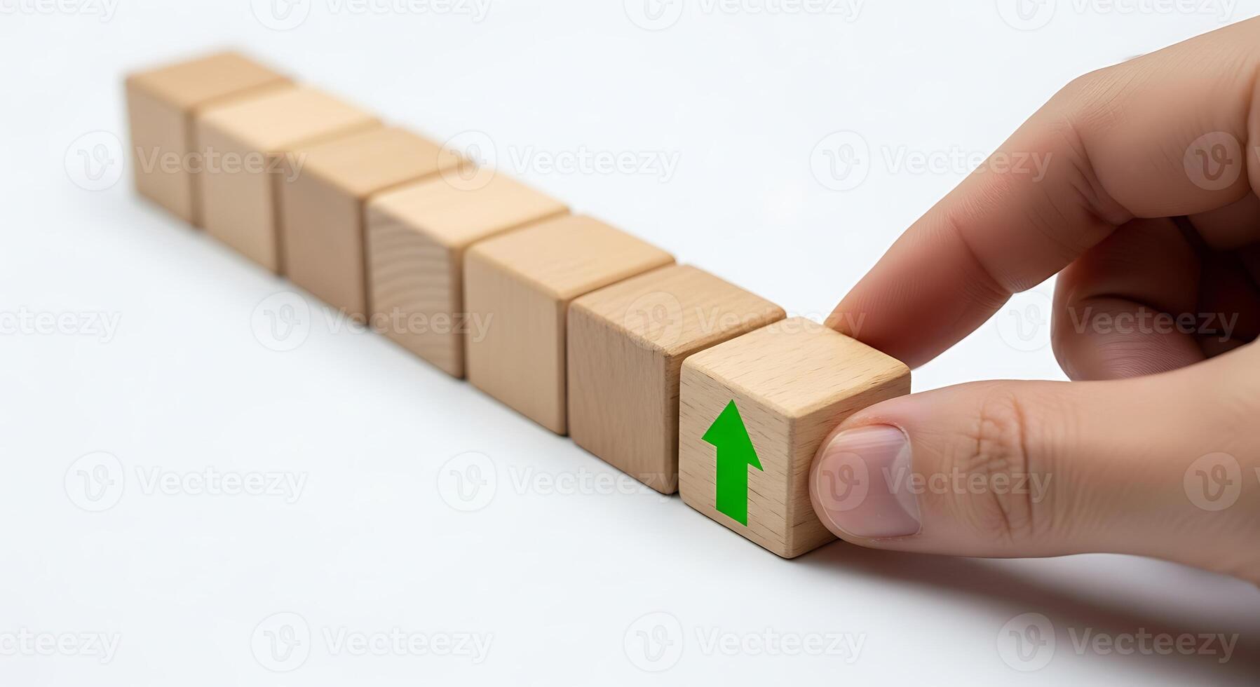 Hand Adjusting Wooden Blocks in a Row with Green Arrow on the Front Block photo