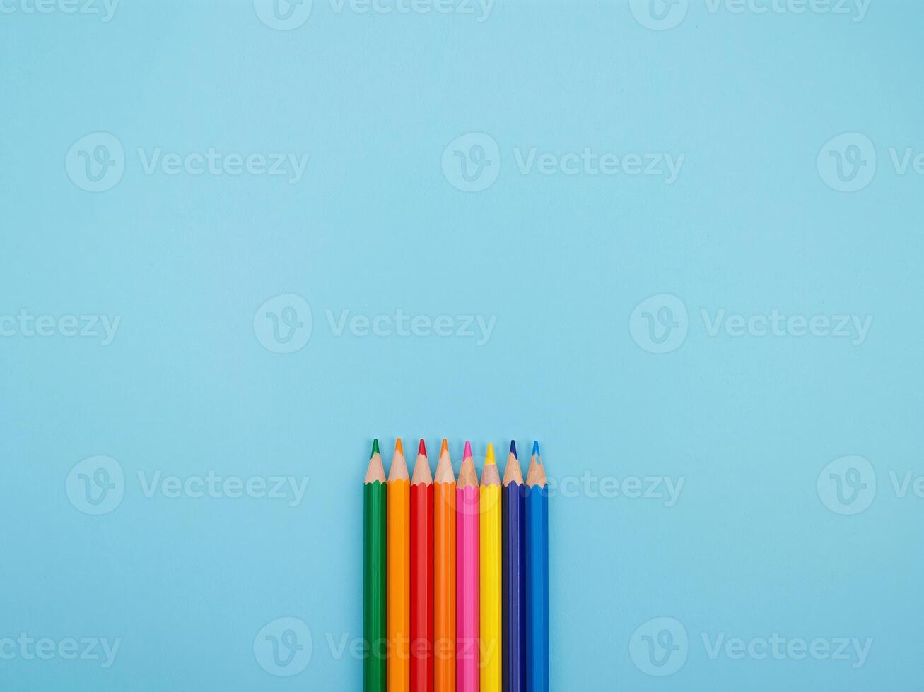 Colored Pencils Array on Light Blue Sharp Points and Wooden Textures Displayed Top View photo