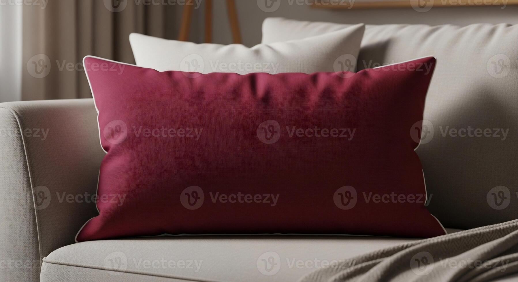 A close-up realistic rendered image of a plush rectangular throw pillow in a deep berry red hue with white piping, resting on a neutral-toned sofa with a soft knitted throw draped over the armrest photo