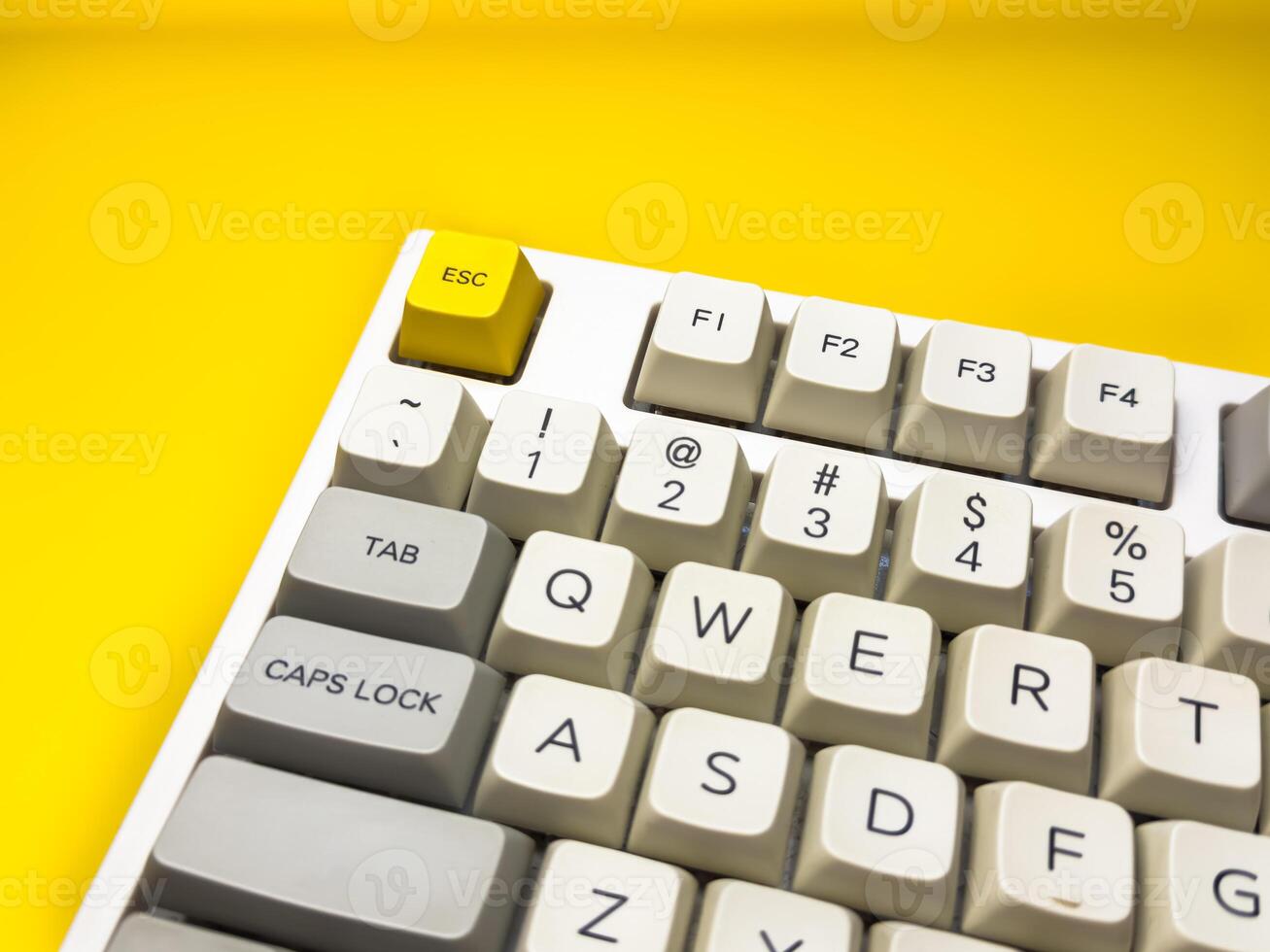 Close up mechanical keyboard with bright Esc key on bright yellow background, minimalism, keyboard buttons. A keyboard with a yellow key on the bottom left photo