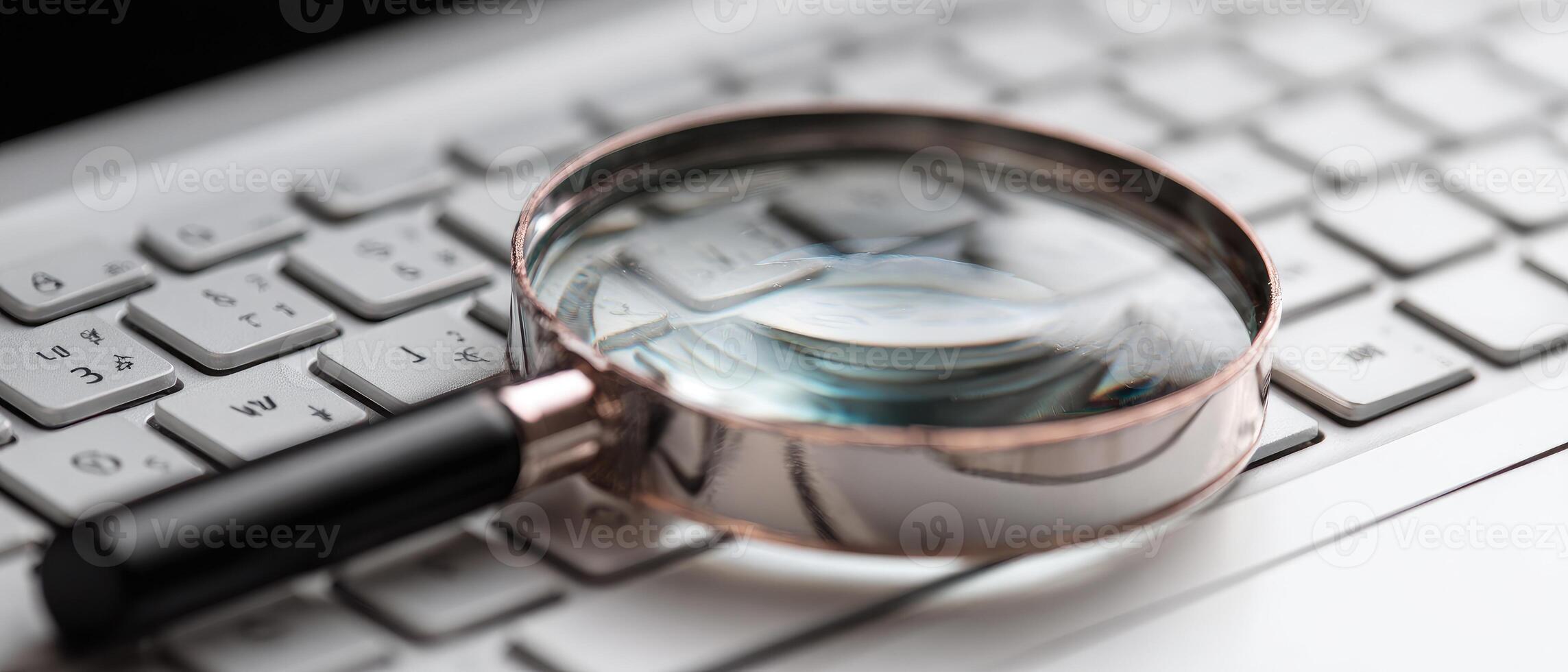 Close-up of a magnifying glass on a white computer keyboard photo