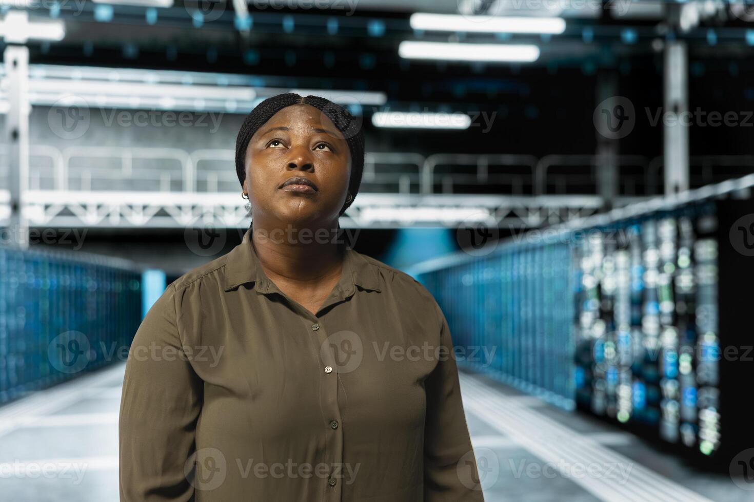 Technician walking in data center with rigs supporting business needs. African american server farm engineer doing checkup, ensuring infrastructure works at optimum performance for smooth operations photo