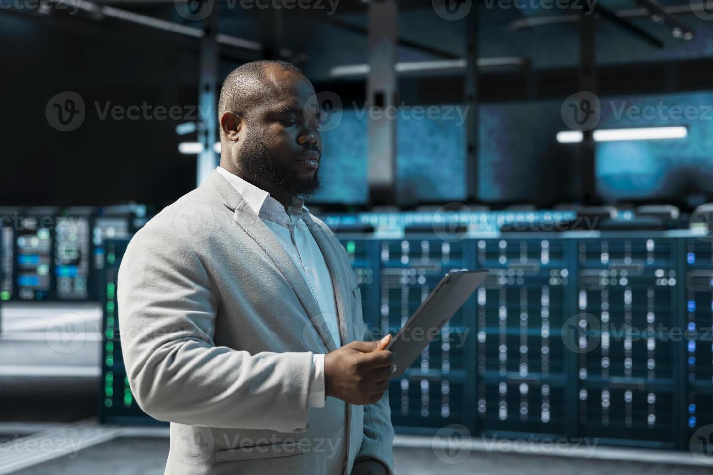 Programmer in data center updating systems using tablet, debugging app performance issues. Server hub IT expert using device, looking for malfunctions, increasing maximum efficiency and uptime photo