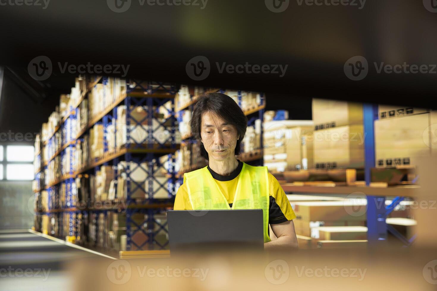 Warehouse employee in workwear preparing packages for local delivery, processing custom orders and handling merchandise within large business operation focused on e-commerce. photo