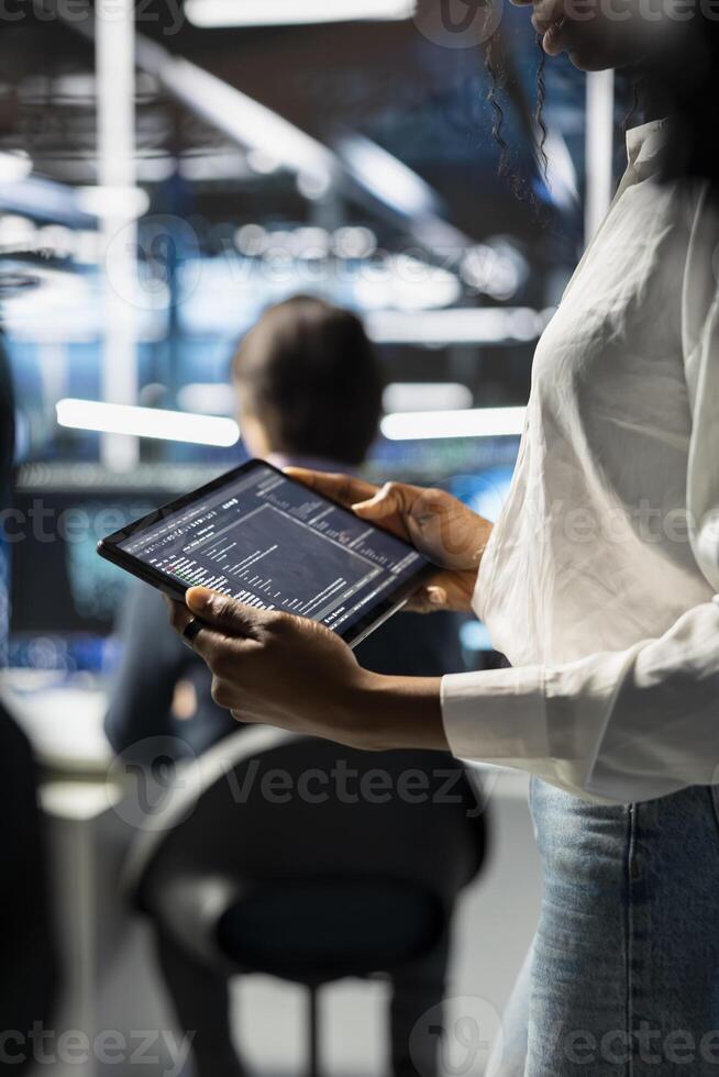 Close up of engineer using tablet, coding in data center, updating neural networks scripts. Worker in server hub programming machine learning algorithms, debugging equipment mainframes photo
