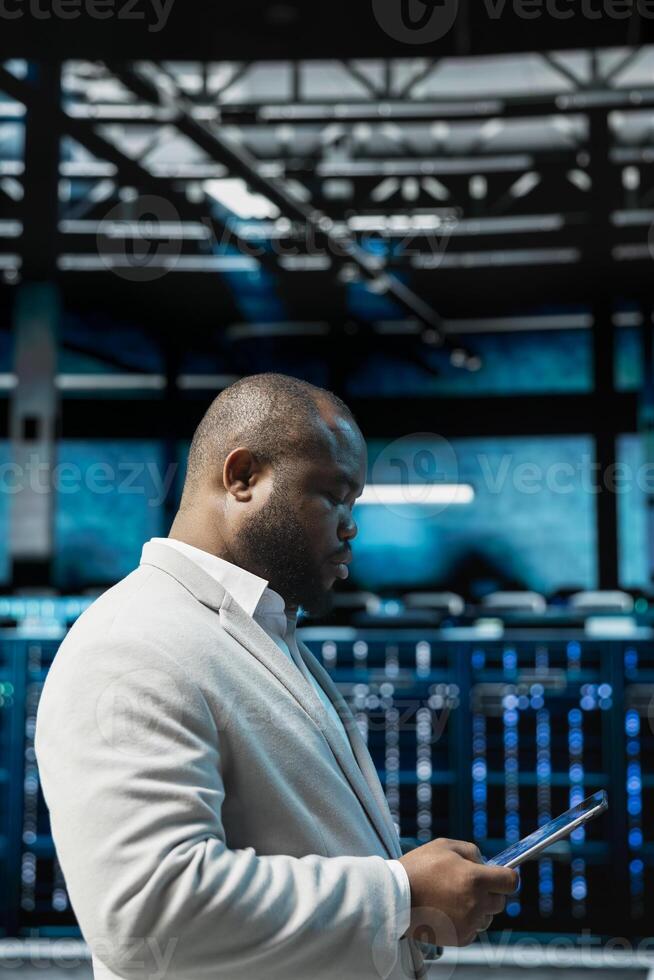 Server hub admin checking recovery plan on tablet, tracking resource utilization trends. Data center IT expert scanning hardware logs for faults, making sure rigs are functioning optimally photo