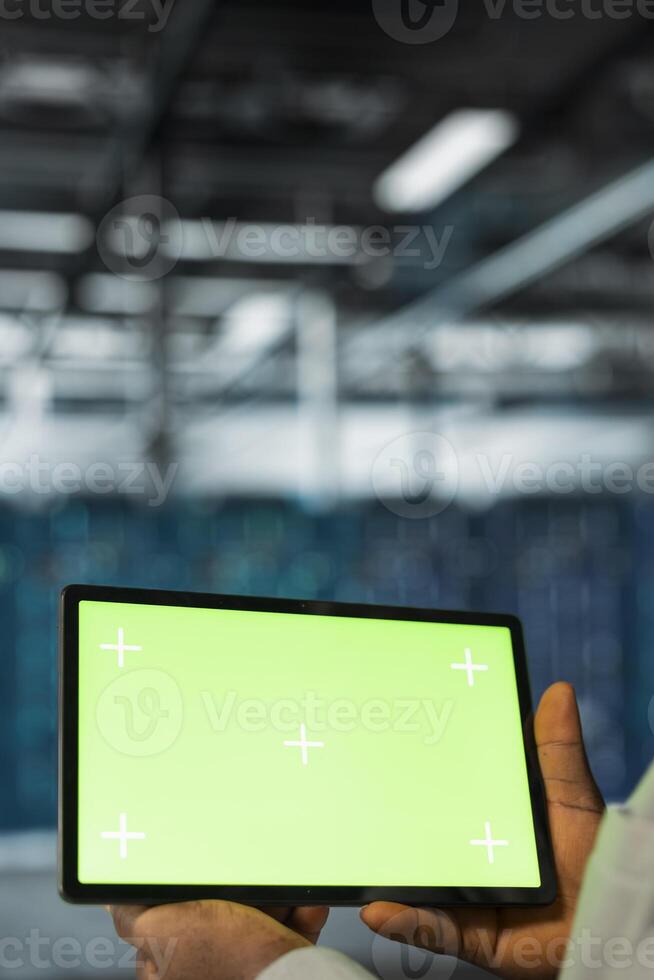 Close up of data center programmer using green screen tablet in data center, reviewing network configuration. Server hub worker using mockup device, scanning hardware logs for faults photo