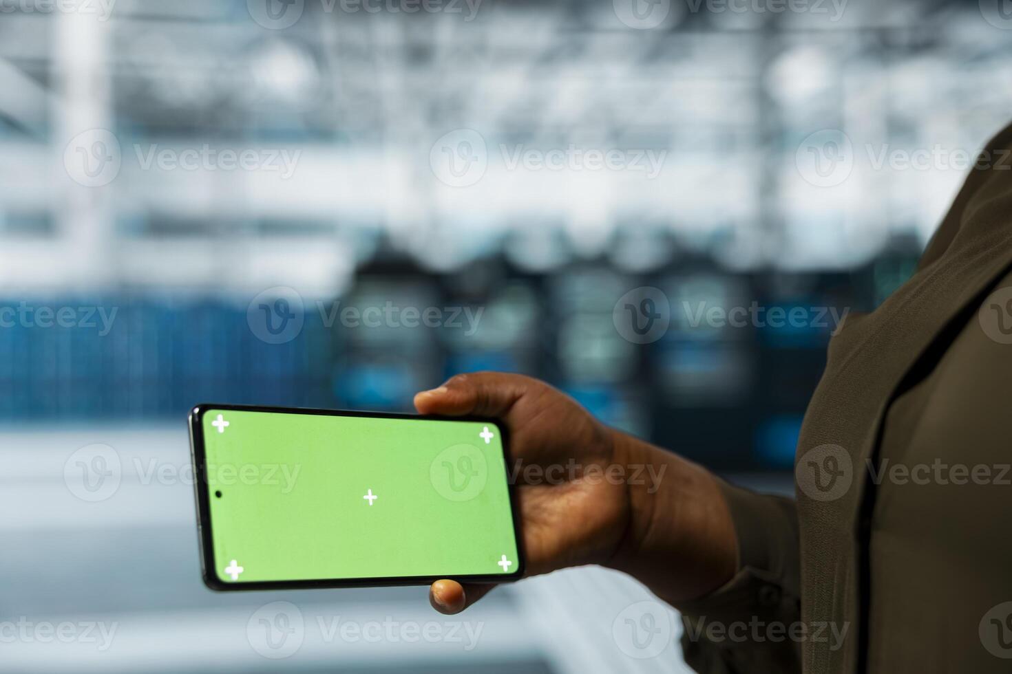 Close up of data center technician checking rigs performance data on chroma key smartphone. Server farm worker using isolated screen mobile phone to look at system alerts, monitoring equipment photo