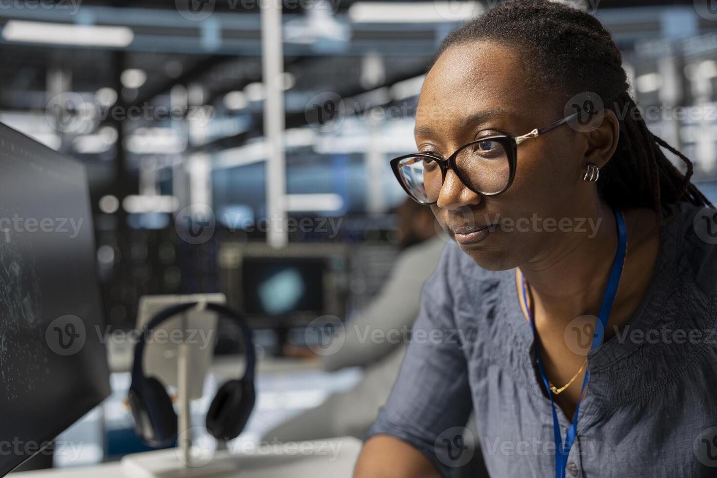 Close up of server hub engineer looking at data visualization on PC to pinpoint equipment performance issues. African american data center worker looks at analysis graph to reduce hardware failures photo