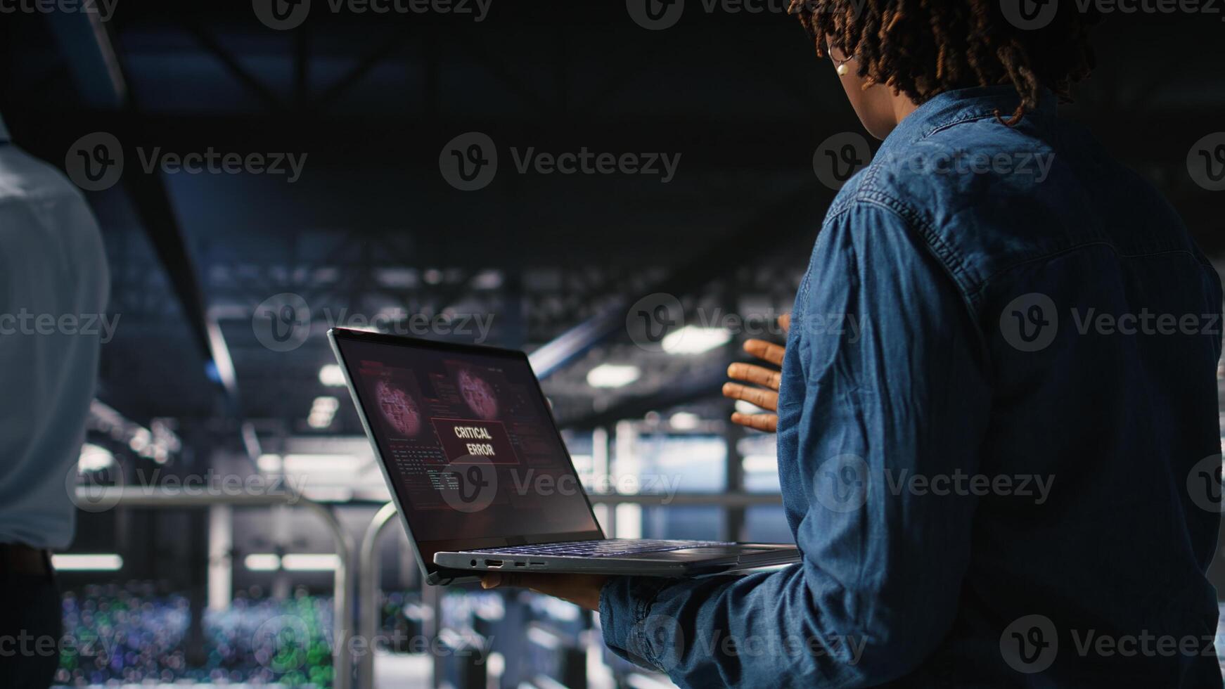 Data center software developer panicking after receiving critical error popup on laptop display. African american woman in server hub alerted by bugs causing low hardware performance, photo