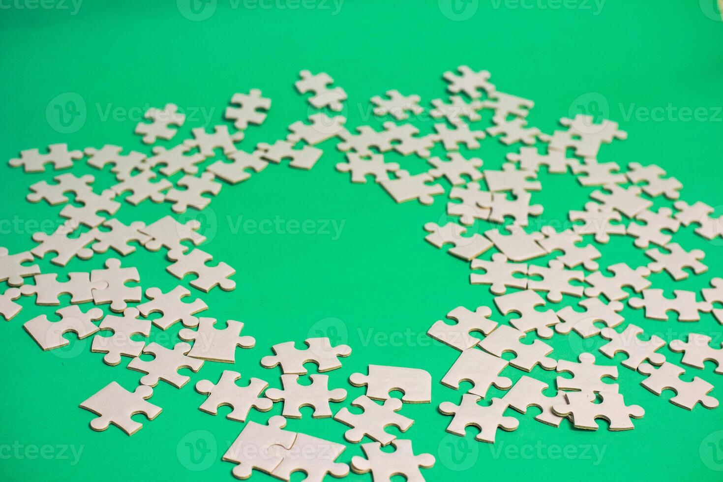 Scattered white jigsaw puzzle pieces on green background, representing incomplete projects and the challenge of finding the solution photo