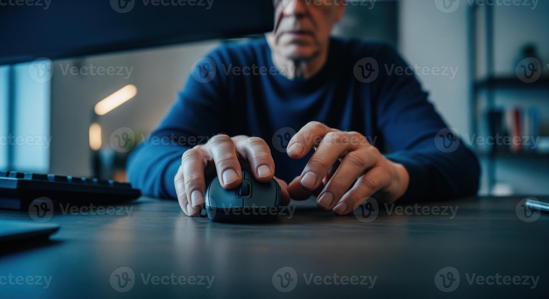 Senior man hands navigating a computer mouse on a dark desk, focused on digital work photo