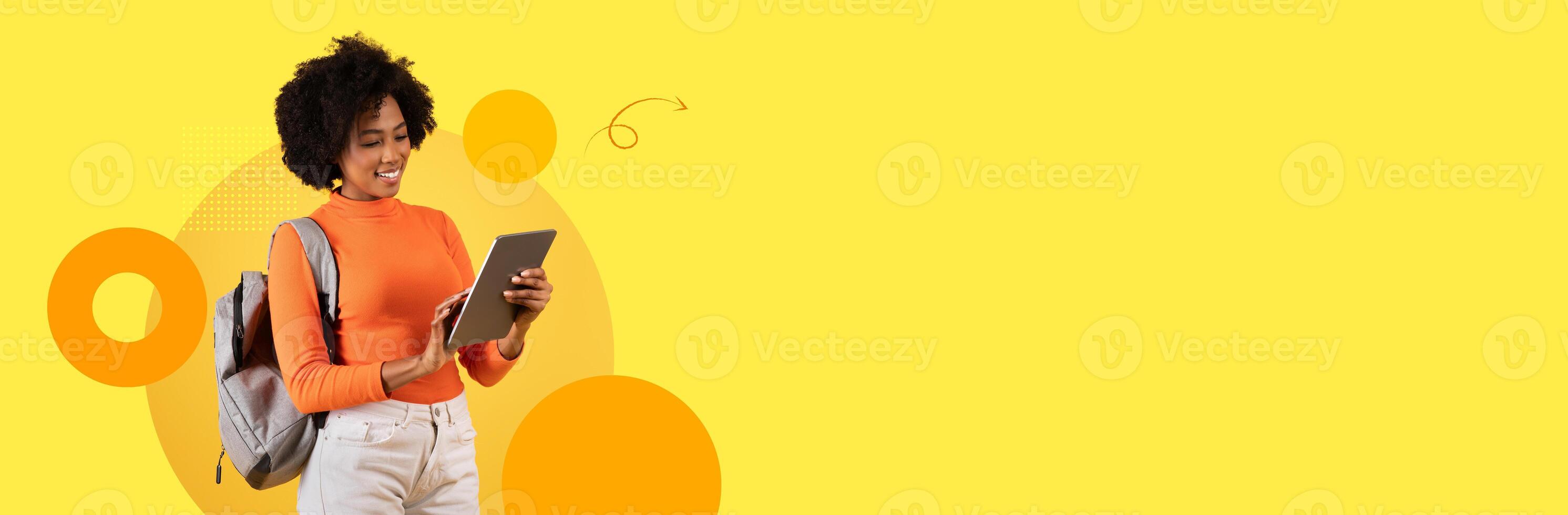 A student stands with a tablet, focused on her studies in a bright, modern educational setting. The background features a cheerful yellow color scheme that enhances the learning atmosphere. photo