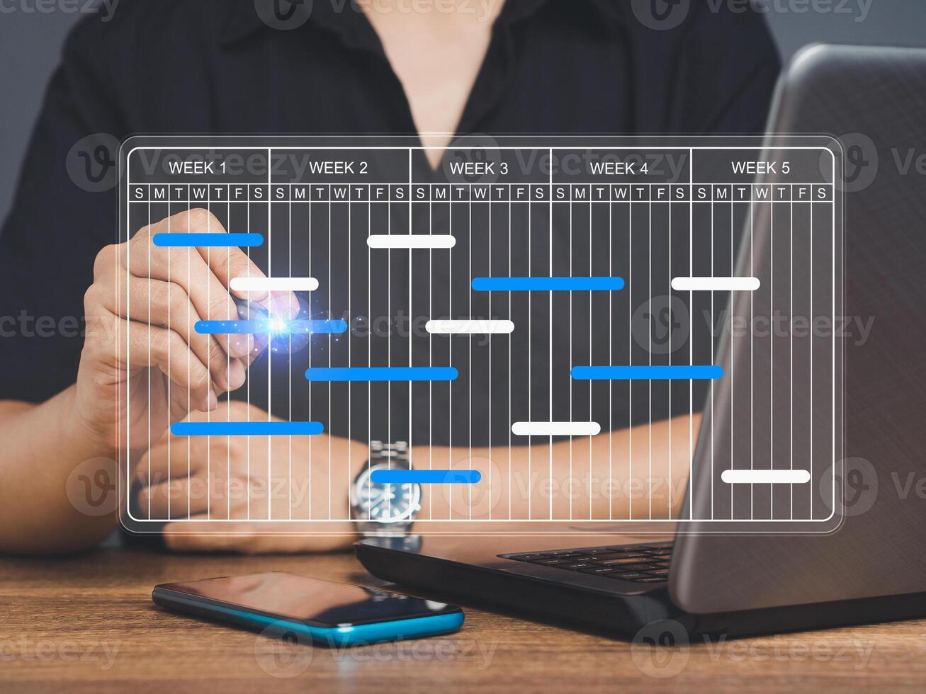 Project manager working on a laptop and updating tasks and milestones progress planning with a Gantt chart scheduling interface on a virtual screen. photo