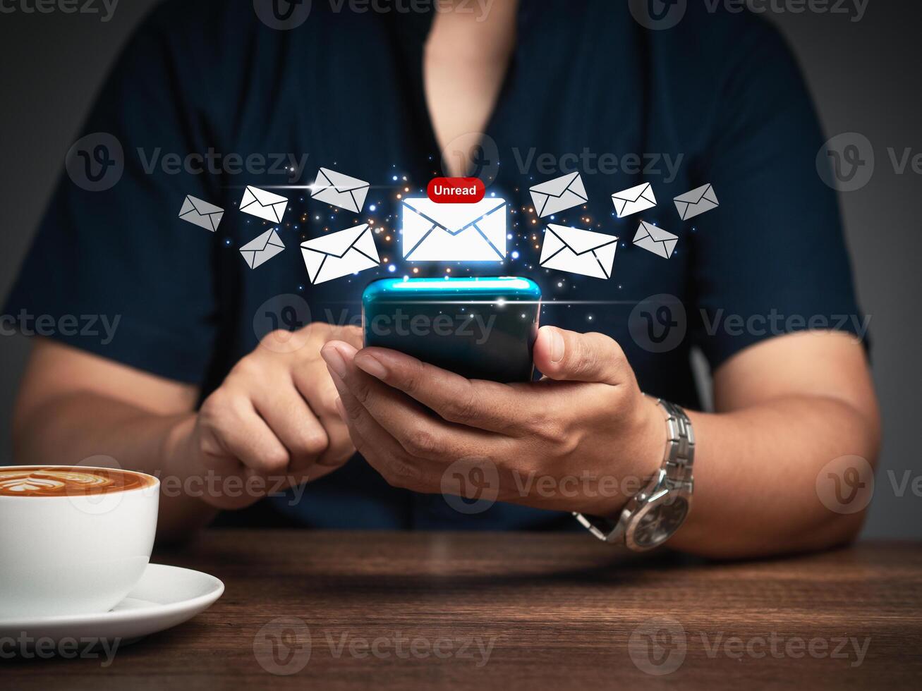 Close-up of a businessman using a mobile receive a new message with email icons while sitting at the table. photo