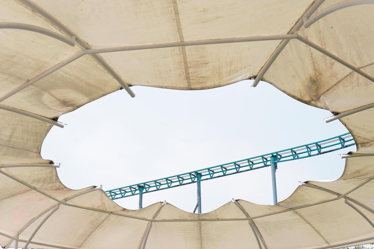 Track of a game ride with a height that is visible in the open dome hole with a blue sky photo