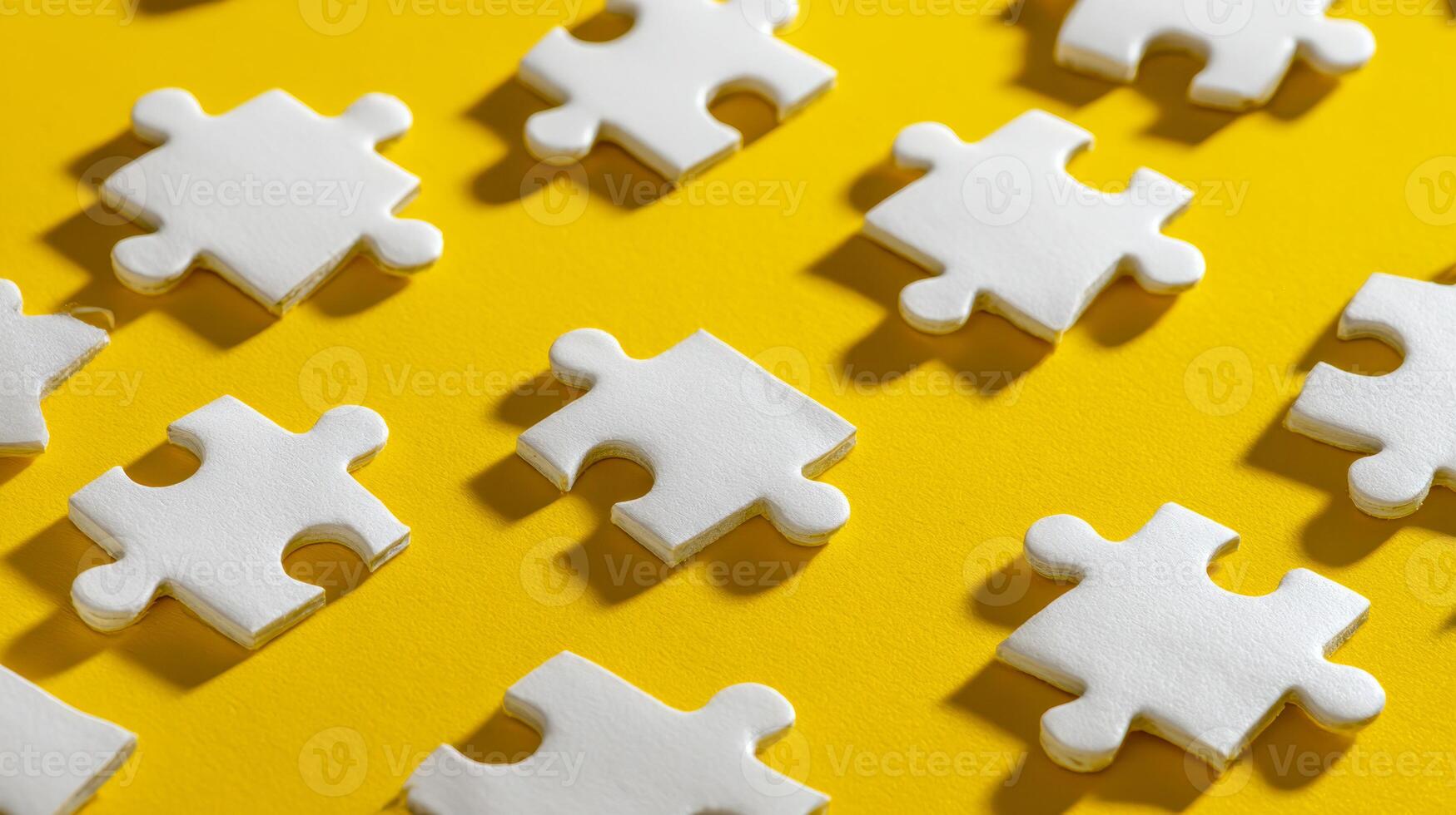 Multiple white puzzle pieces arranged in an orderly pattern on bright yellow background symbolizing problem solving and organization concepts in creativity and teamwork photo