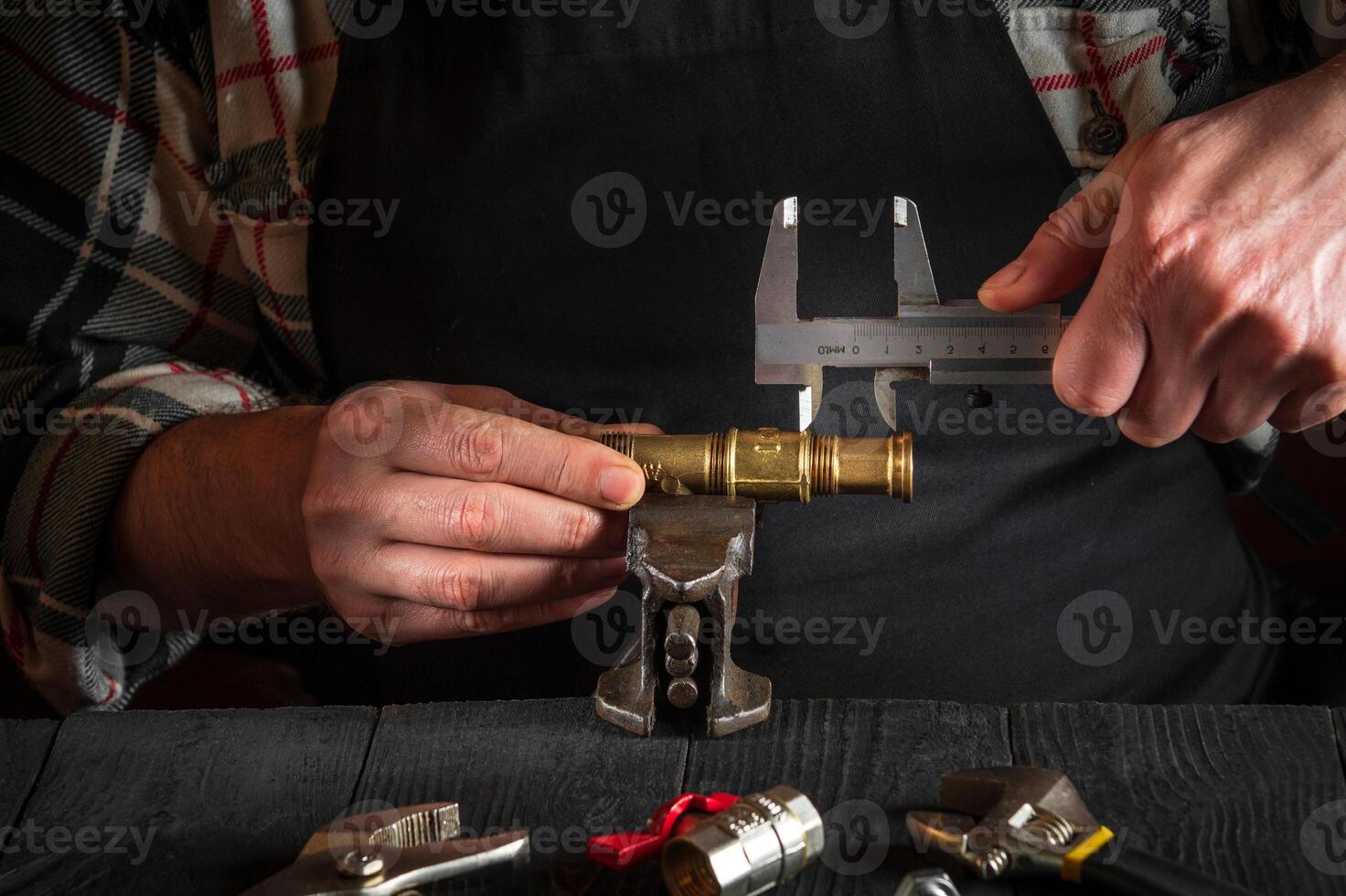 Master plumber measures the size of fitting using a caliper before connecting water or gas pipe. Close-up of the hands of the master in workshop photo