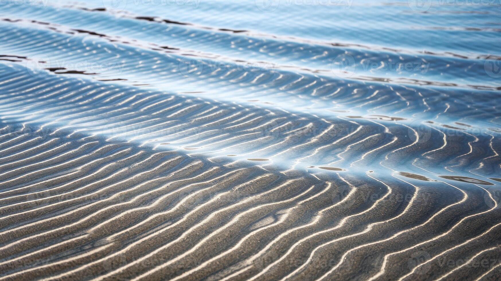 Shallow Water and Sand Patterns Create Peaceful Scene on a Beach During a Sunny Day photo