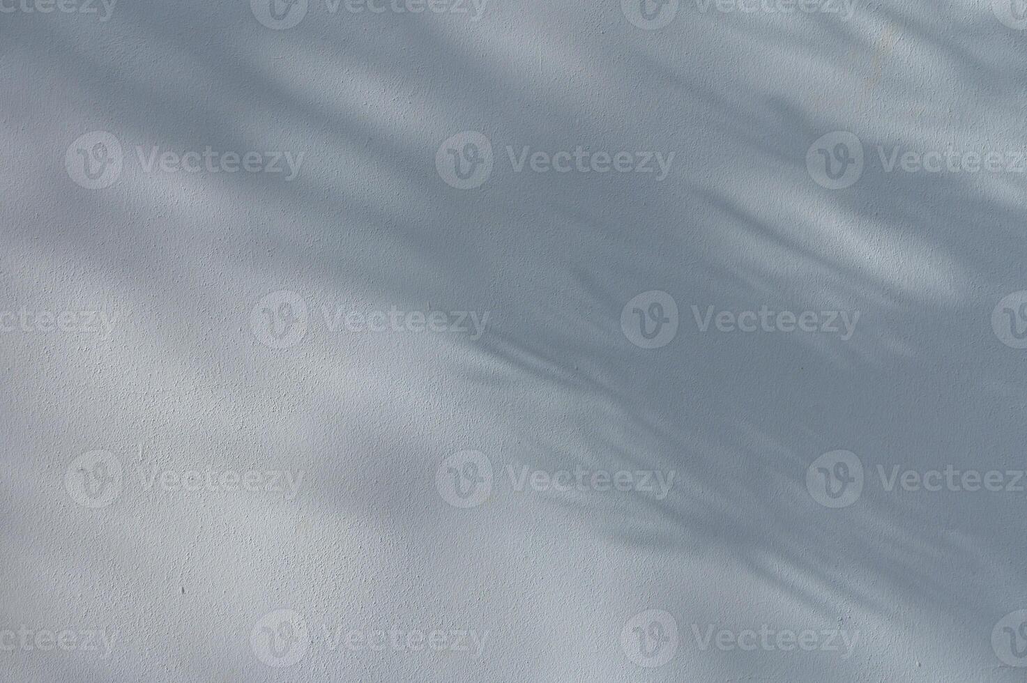 Soft shadows of leaves cast on a house wall in sunlight. Natural abstract background with light and texture. Calm summer atmosphere in a Mediterranean setting. photo