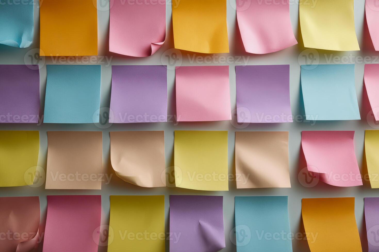 Colorful sticky notes arranged in a grid pattern displaying a variety of pastel shades with subtle shadows and curled edges creating an organized background scene photo