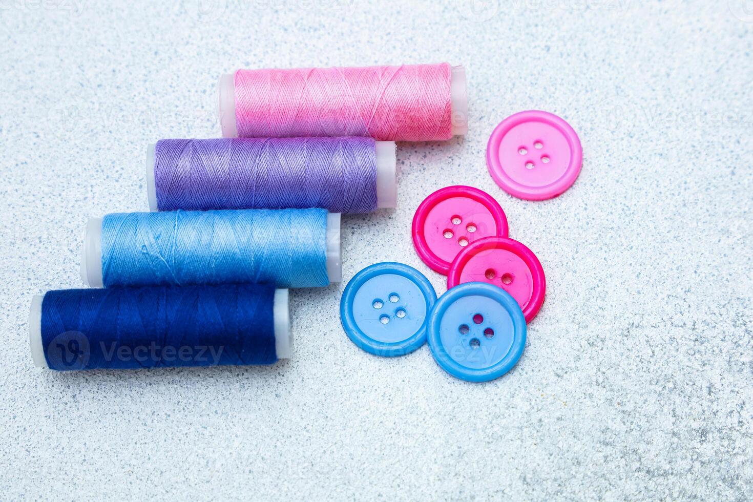 Colorful sewing threads and buttons arranged on a light surface for crafting projects photo