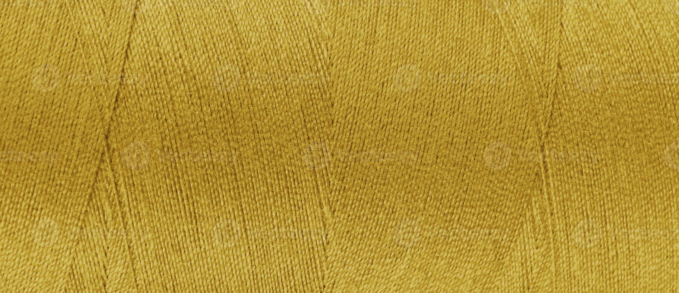 Texture of yellow color threads in spool close up, macro. Wide banner, header photo