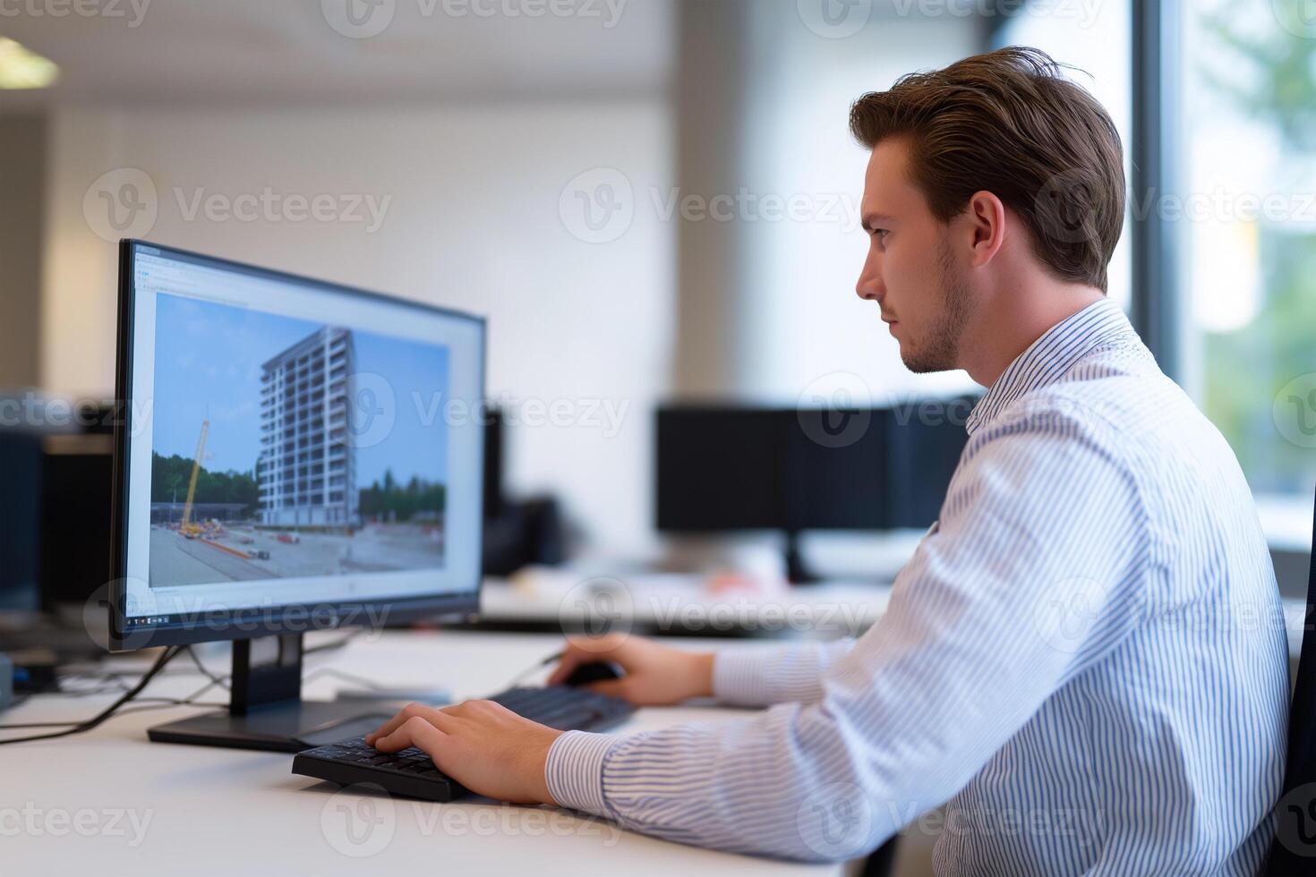 A man is working on a computer with a building on the screen photo