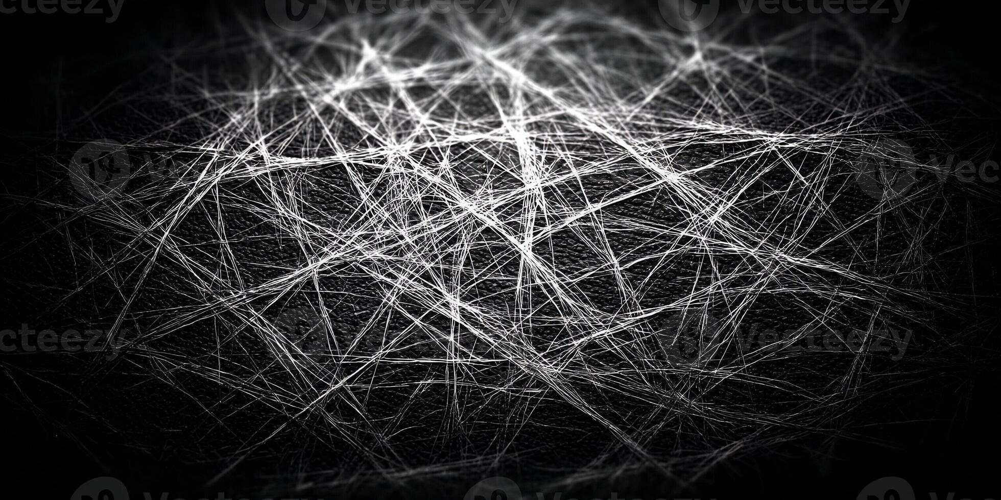 White abstract scratches create a tangled web design on a dark black textured surface photo