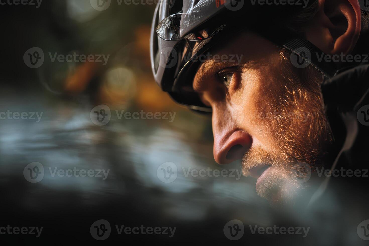 Focused cyclist wearing a helmet gazes intensely, with blurred background suggesting motion. His face is partially in shadow, highlighting determination and concentration. No text visible photo