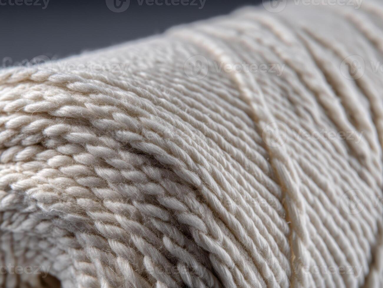 A close-up of a spool of light-colored twine with tightly wound strands, showcasing the texture and intricacy of the fiber. The focus is on the detailed pattern of the yarn photo