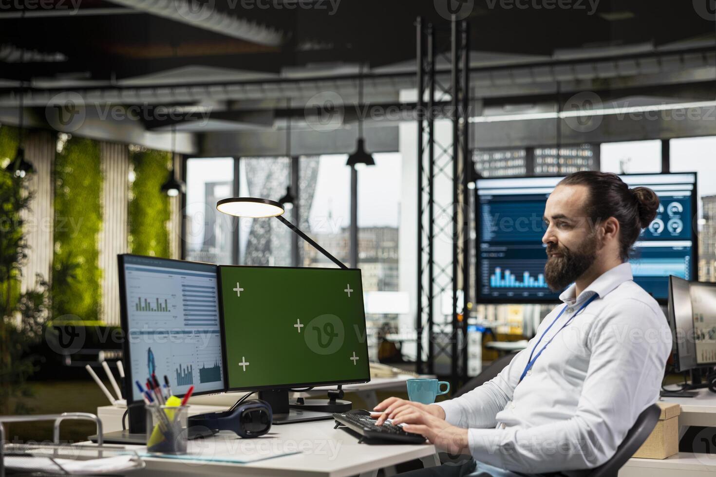 Corporate professional works on report writing next to green screen, reviews analytics in the office for a new business strategy. Using KPI insights to enhance efficiency and progress. photo