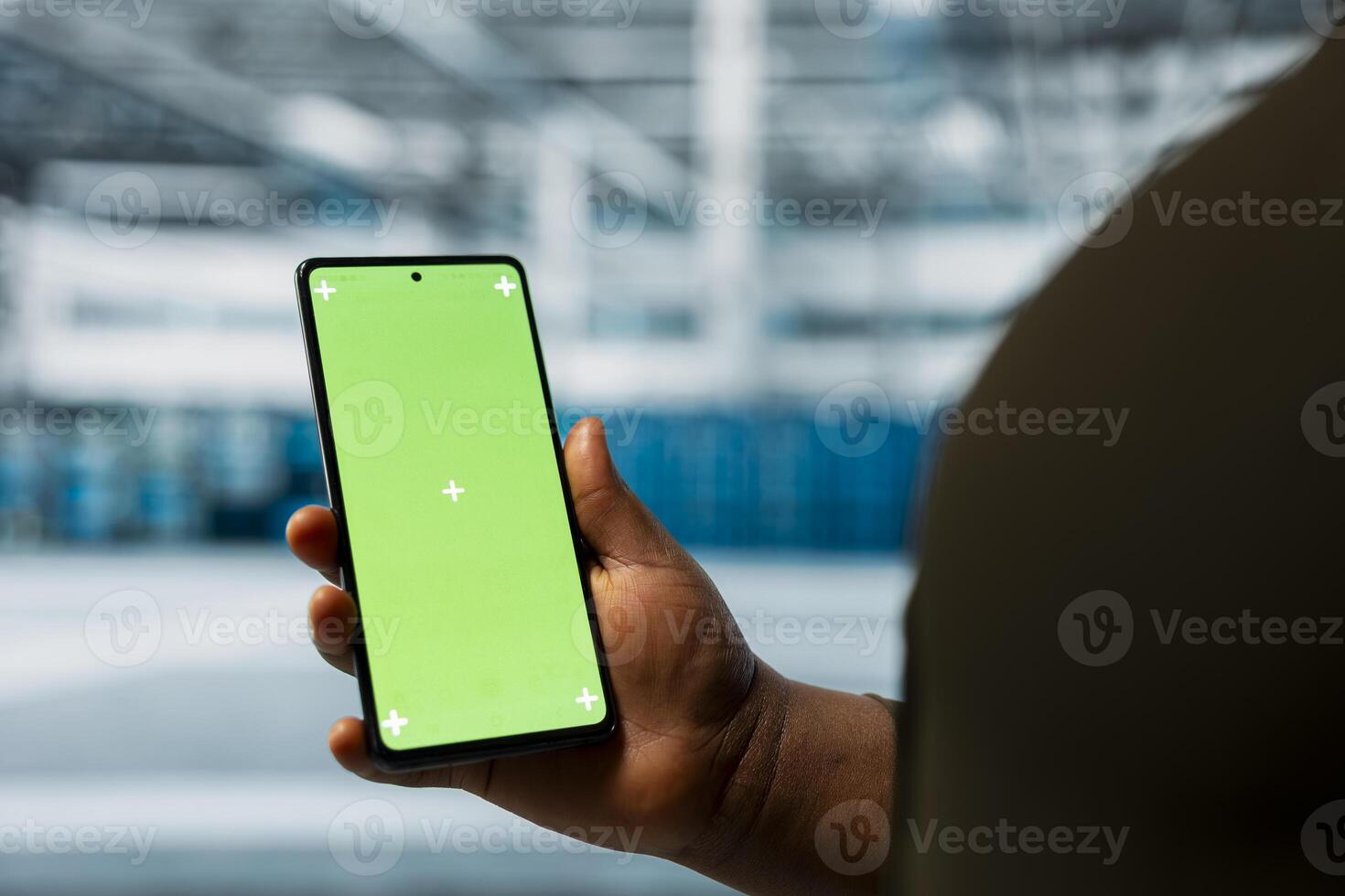 Close up of data center admin using green screen smartphone to monitor infrastructure network performance. Server room employee checks gear functionality using mockup mobile phone photo