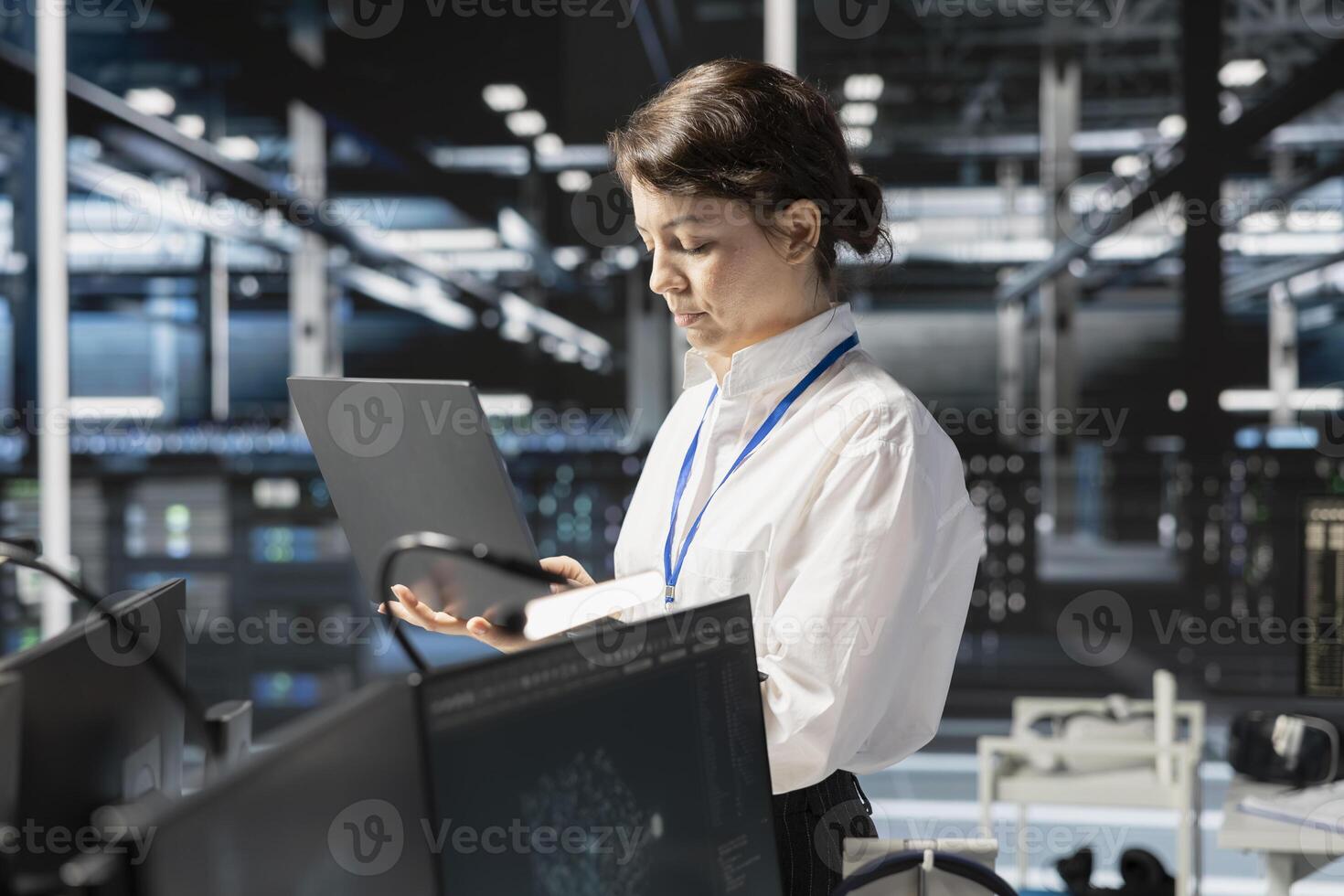 Data center programmer running diagnostic scripts on laptop, examining infrastructure. Server room IT specialist using notebook to evaluate metrics, running tests to maintain system stability photo