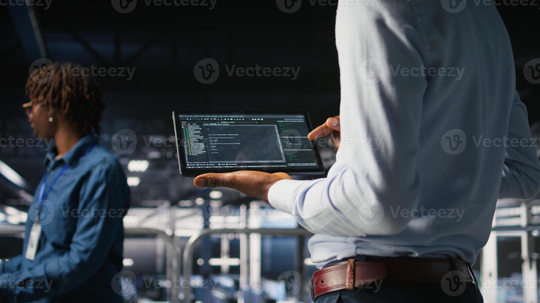 Close up of programmer swiping on tablet display in data center, doing maintenance tasks, ensuring optimal performance. IT expert checks code on device, applying patches to improve stability, photo