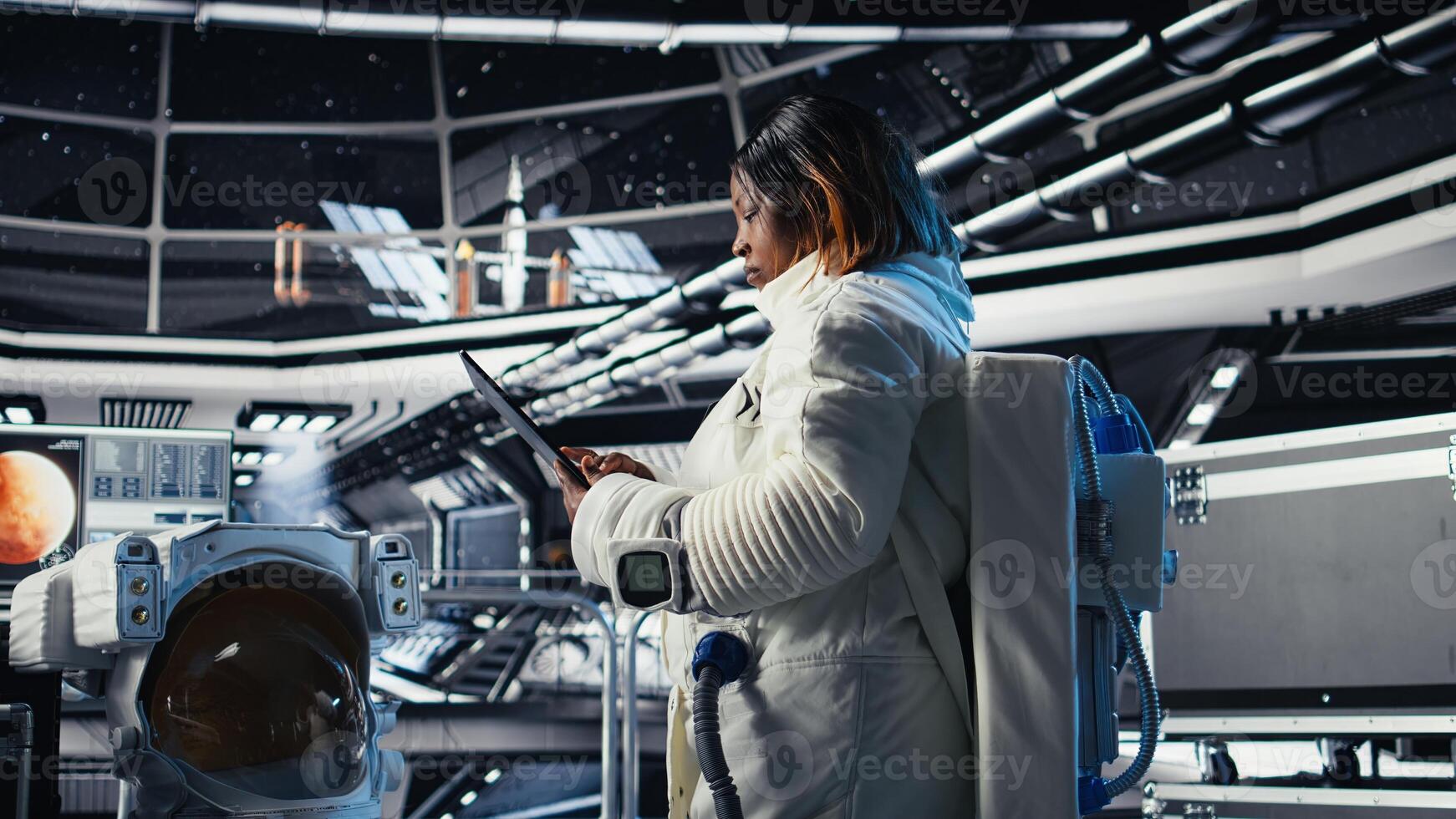 Astronaut inside high tech spacecraft checking red planet summary analytics during routine mission check. Orbit station cosmonaut using device, standing near monitor showing Mars data photo