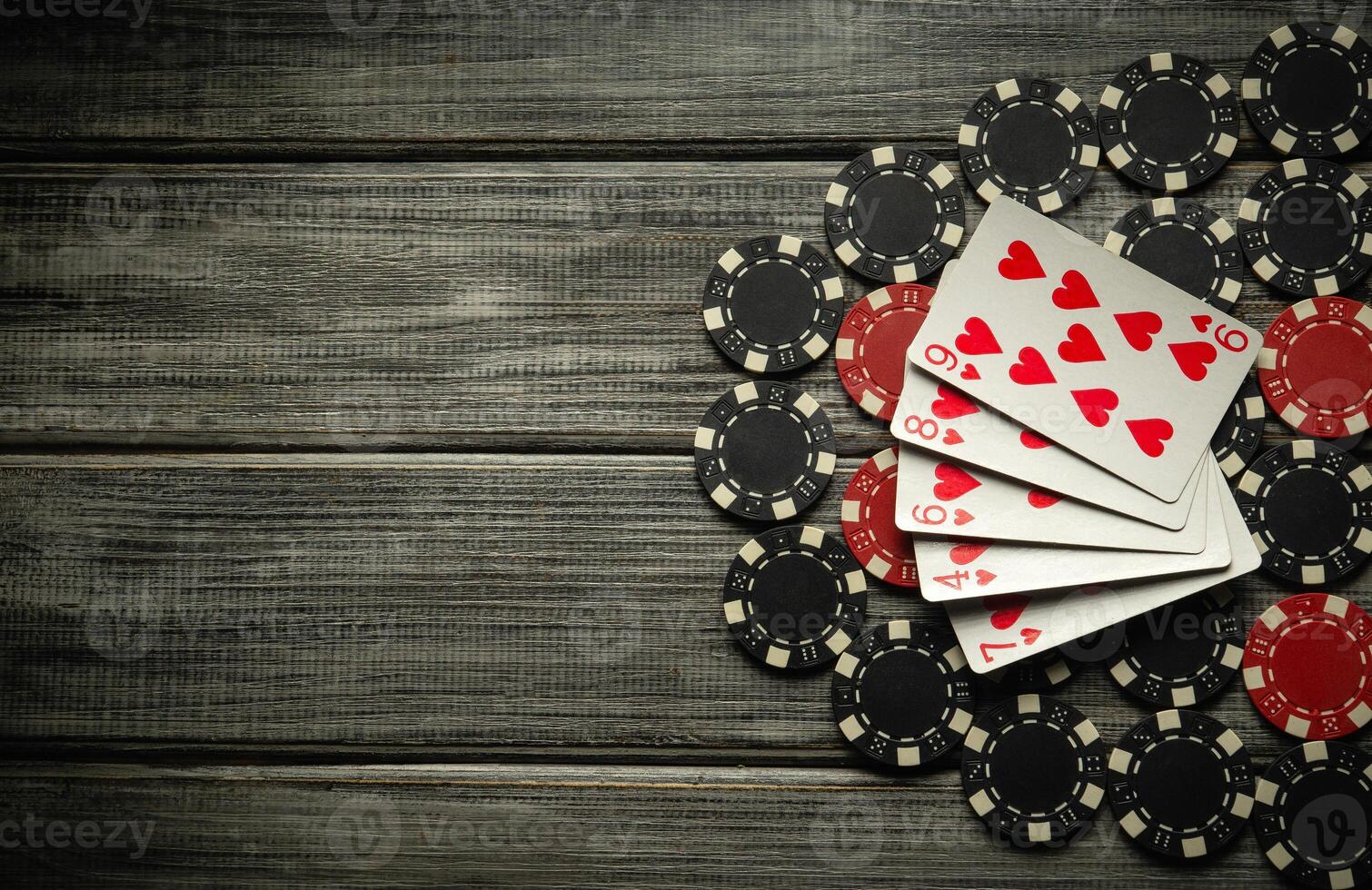 A layout of playing cards featuring flush and assorted poker chips is arranged on a rustic wooden table. This setup creates an inviting atmosphere for a friendly game night photo