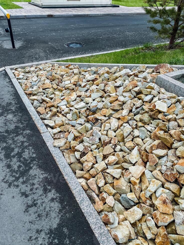 There is a sizable pile of rocks situated on the side of a road, which may include various types of stones like pebbles, rubble, and gravel that serve as building materials photo
