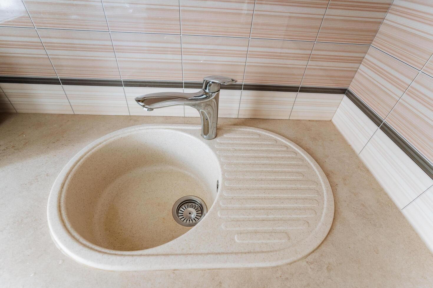 This modern kitchen sink features an elegantly designed faucet that adds sophistication and a practical integrated drainboard, enhancing both functionality and style in your kitchen photo