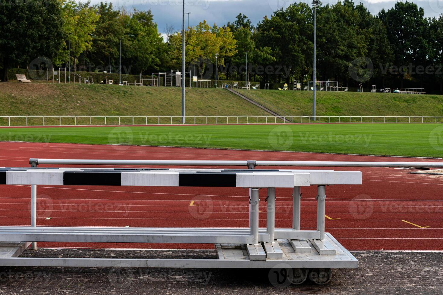 A track field features hurdles placed on the red running surface. In photo