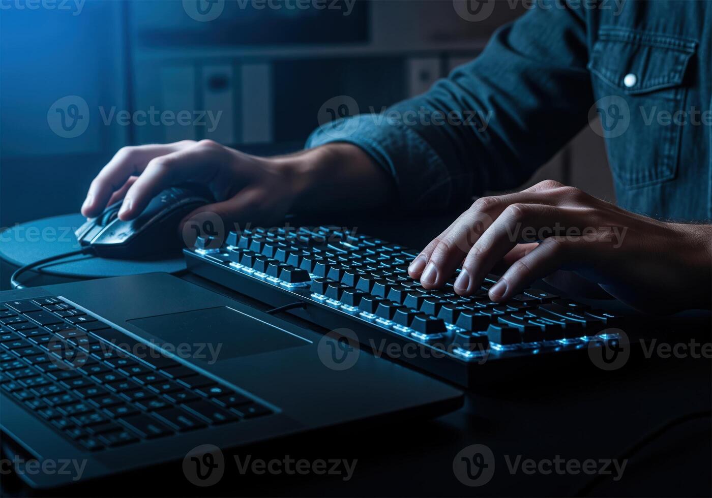 Hands typing on a backlit keyboard and using a computer mouse at a desk photo
