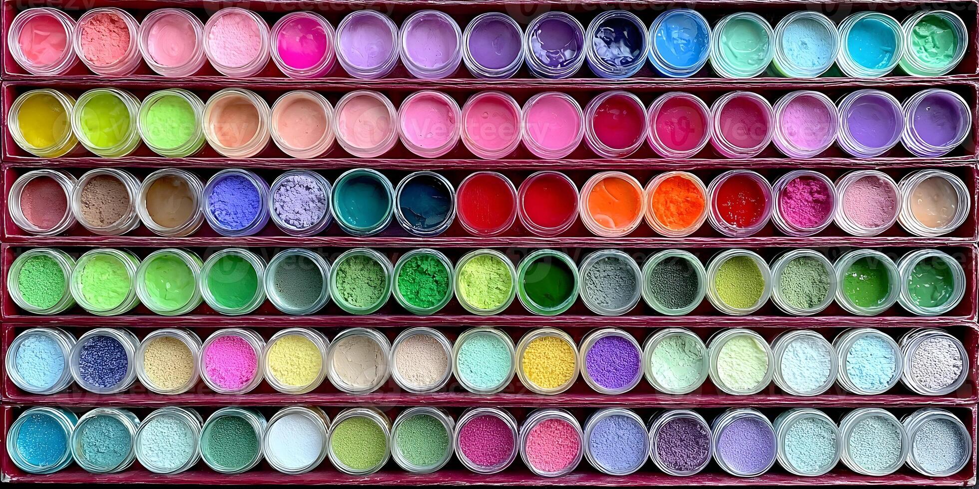 An overhead view of numerous small clear jars filled with vibrant colorful powders and gels neatly displayed in rows on shelves photo