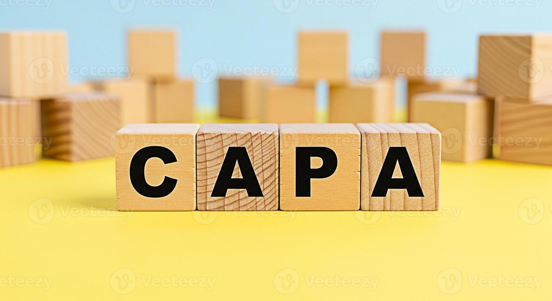 Wooden blocks spelling CAPA on a yellow surface representing corrective and preventive actions in a business setting conveying a sense of structured problemsolving and continuous improvement photo