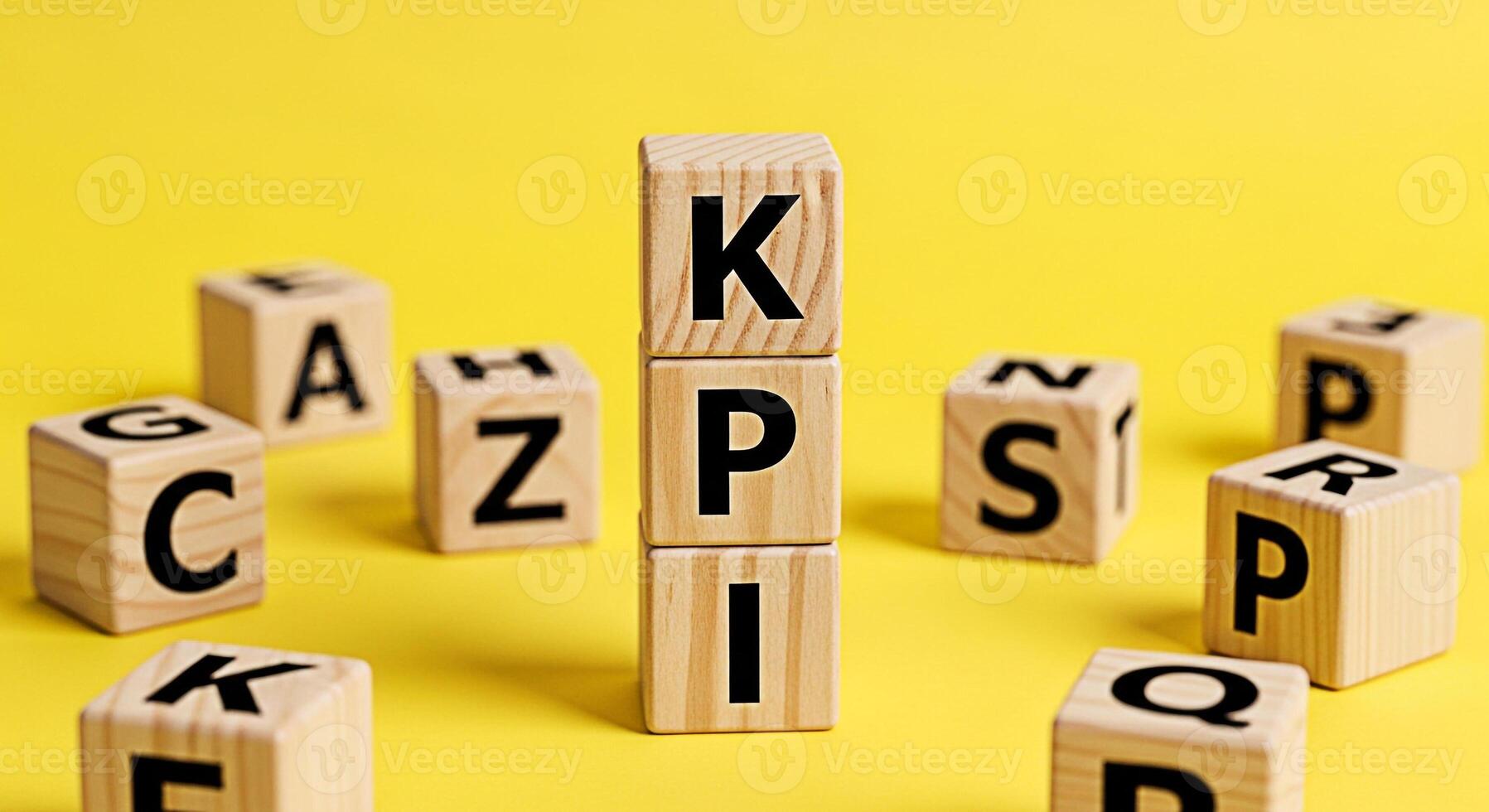 Wooden blocks spelling out KPI standing tall on a vibrant yellow background surrounded by alphabet blocks representing key performance indicators and business success conveying a sense of focus and ac photo