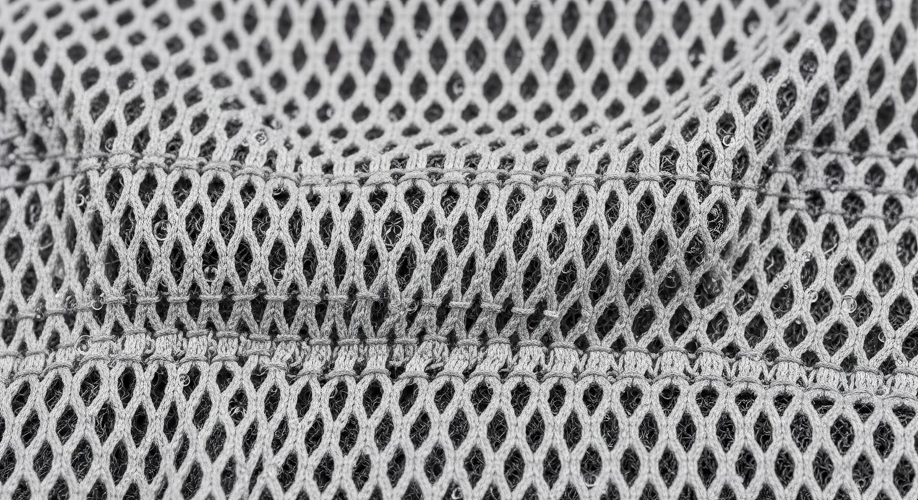 Close-up shot of a gray mesh fabric, highlighting the intricate diamond-shaped patterns and textures, perfect for backgrounds and design elements photo